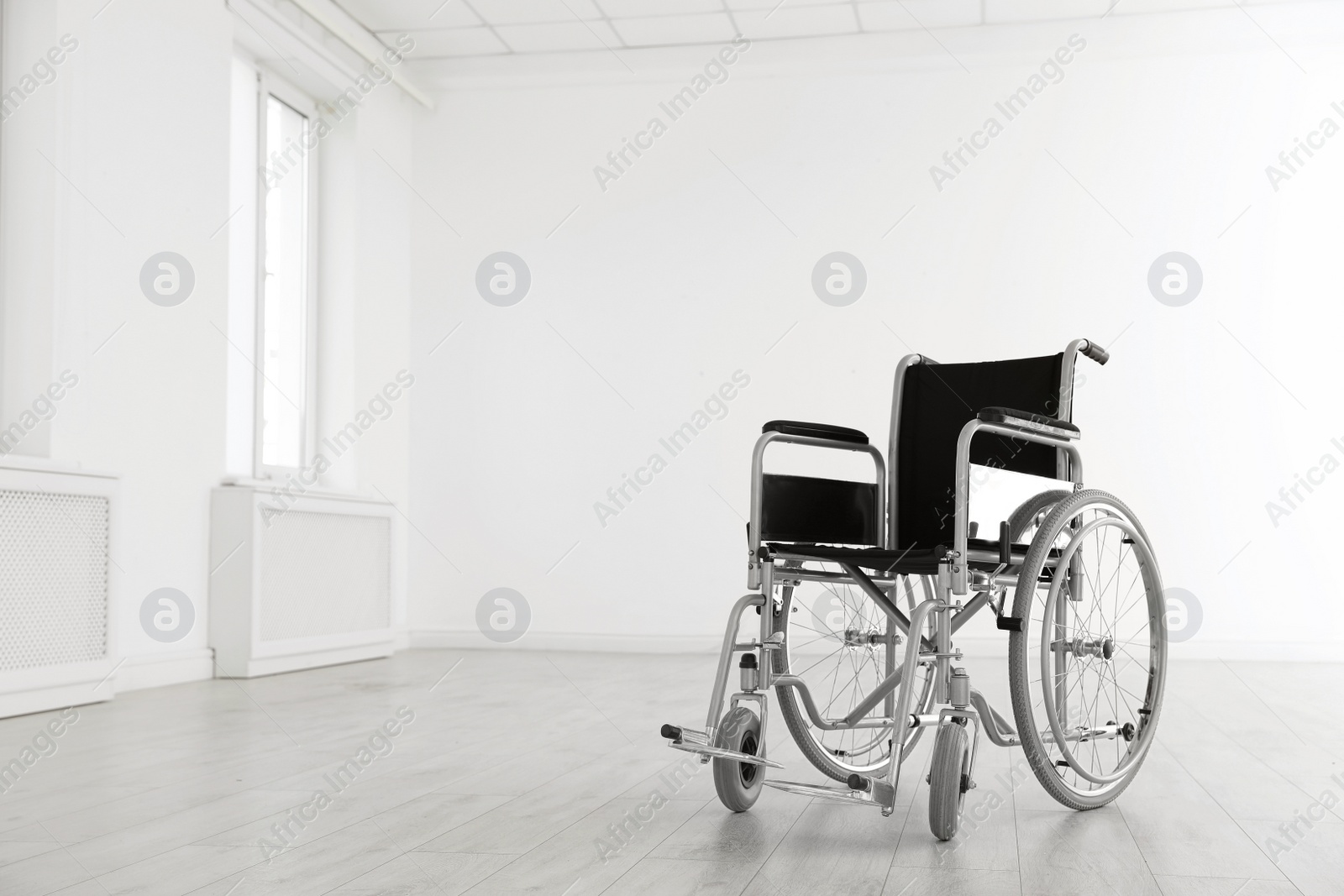 Photo of Modern wheelchair in empty room, space for text. Medical equipment