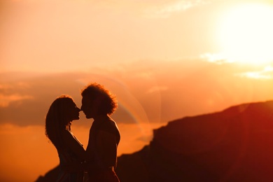 Photo of Young woman in bikini and her boyfriend on beach at sunset. Lovely couple
