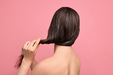 Photo of Woman applying hair mask on pink background