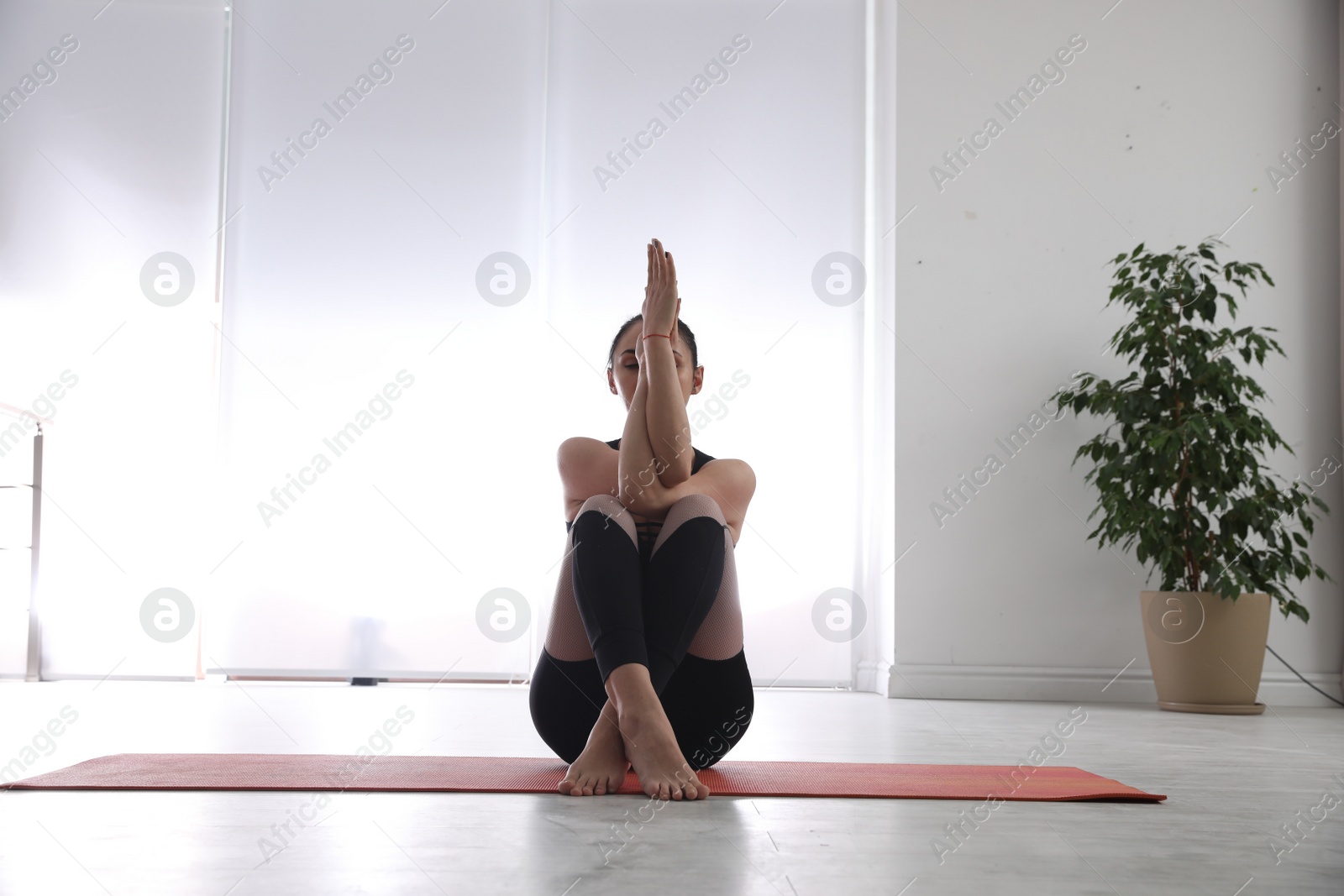Photo of Woman practicing eagle asana in yoga studio. Garudasana pose