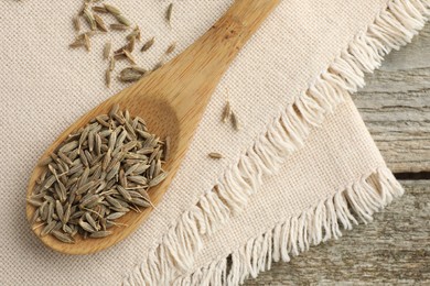 Photo of Spoon with caraway seeds and napkin on wooden table, top view. Space for text