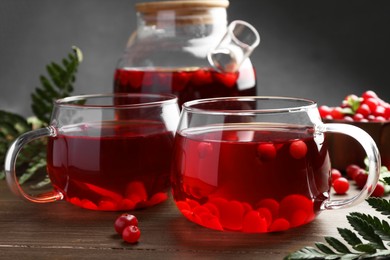 Photo of Tasty hot cranberry tea in glasses and fresh berries on wooden table