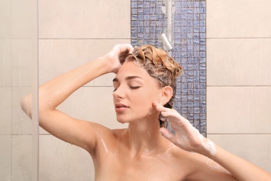 Beautiful young woman taking shower at home