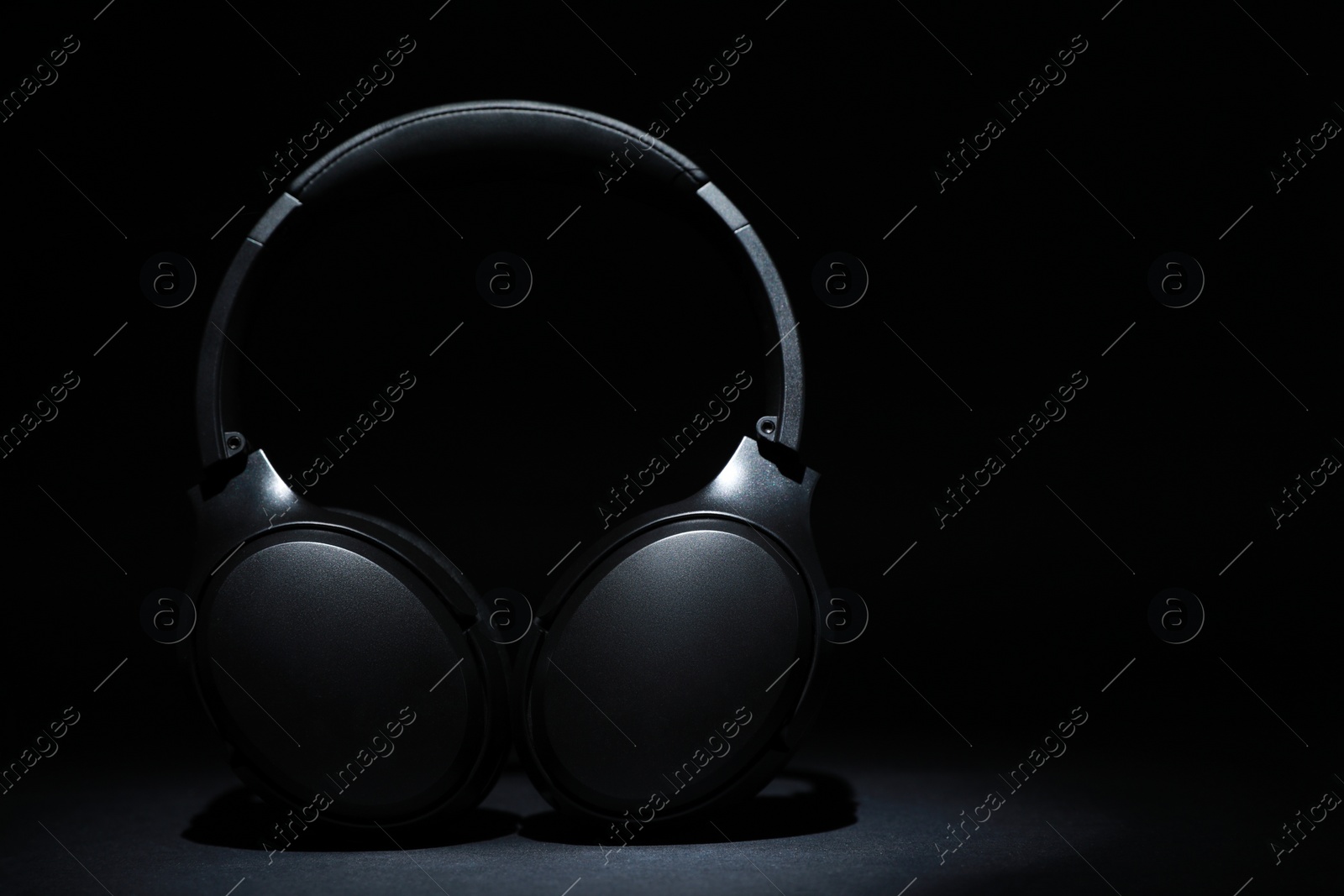 Photo of Modern wireless headphones on black background, space for text