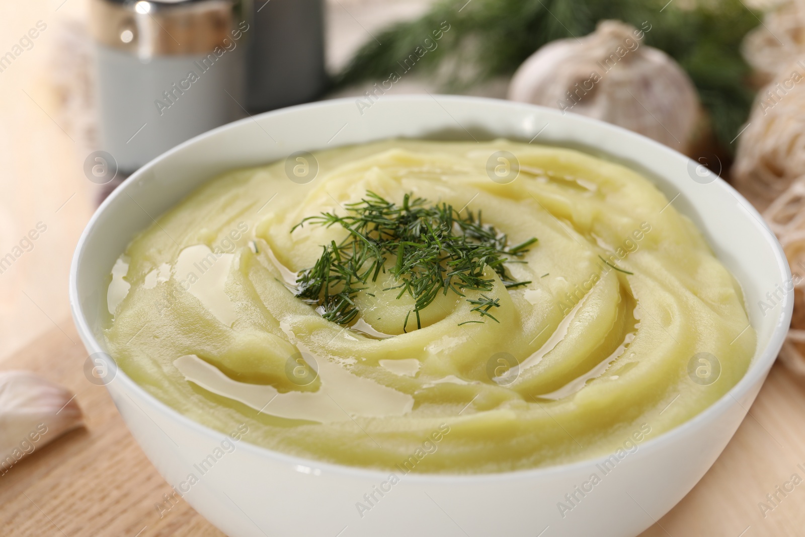 Photo of Bowl of tasty cream soup with dill on wooden table, closeup