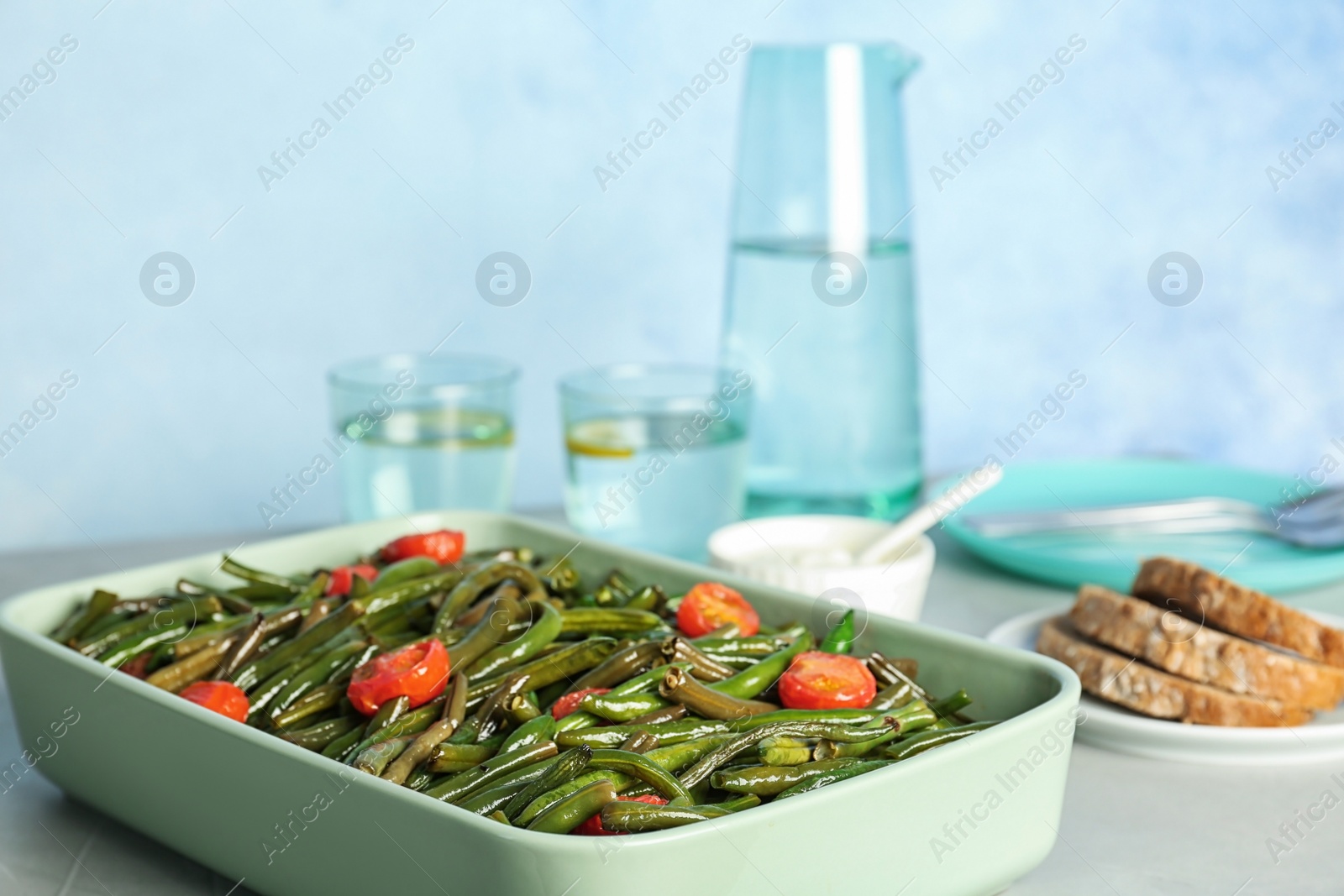 Photo of Dish with tasty green beans and tomatoes on table