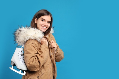 Photo of Happy woman with ice skates on light blue background. Space for text