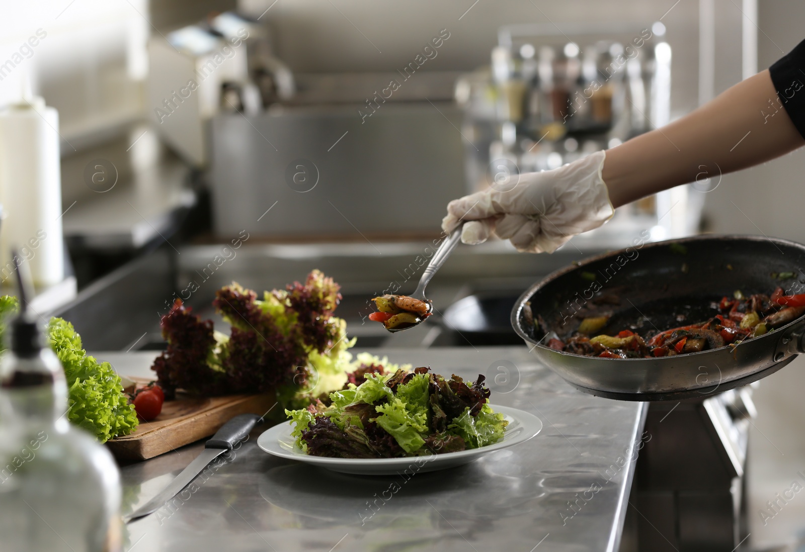 Photo of Female chef cooking tasty food in restaurant kitchen, closeup