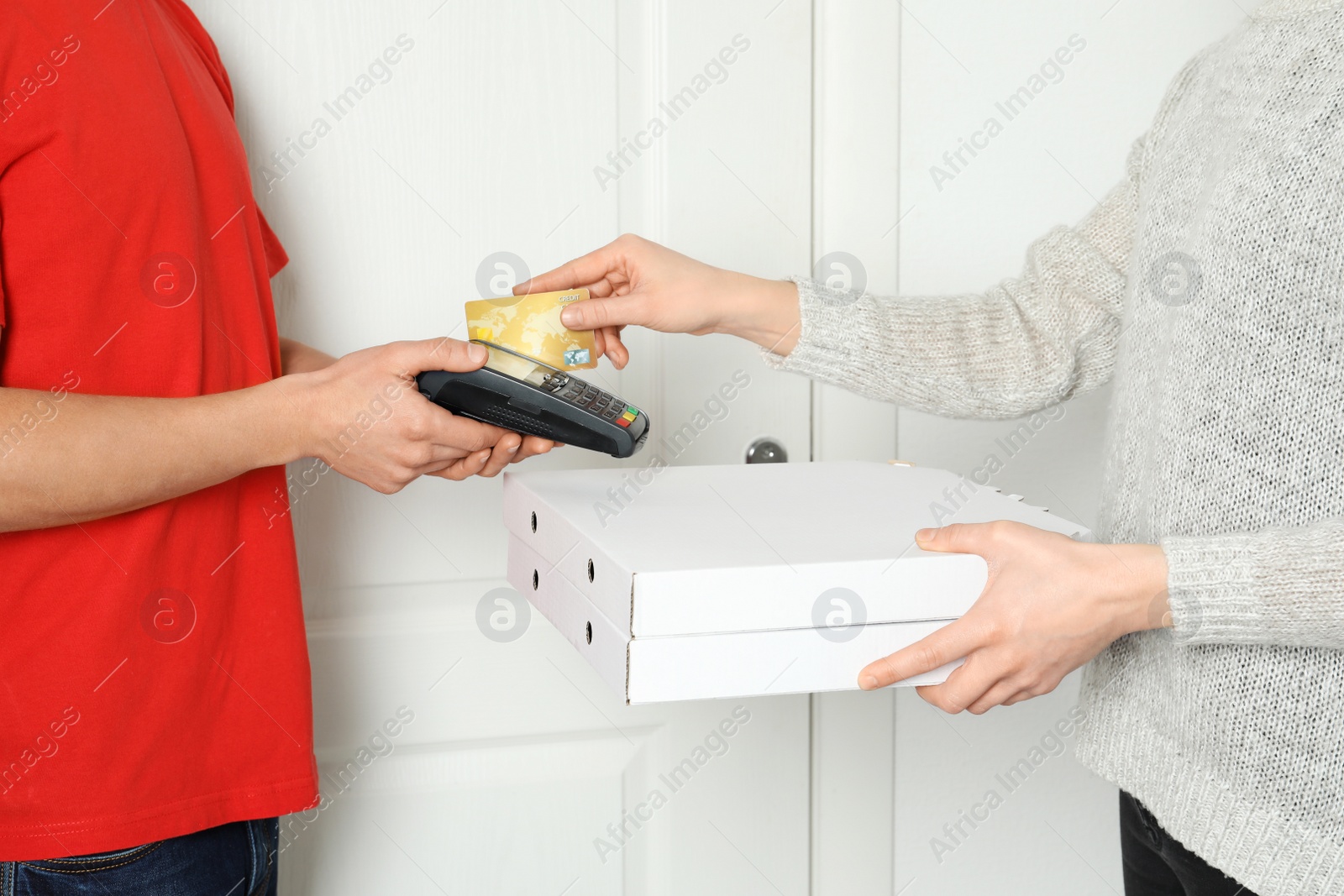 Photo of Young woman using bank terminal to pay for food delivery at doorway, closeup. Ordering pizza