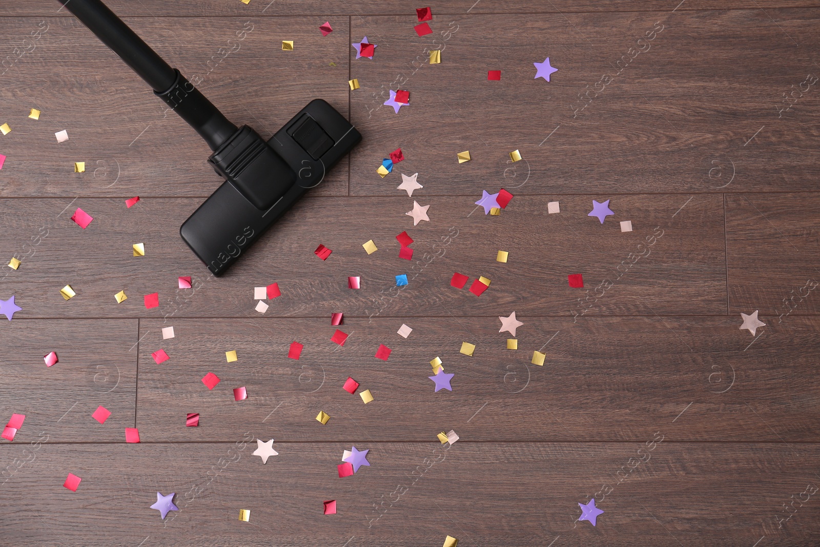 Photo of Vacuuming confetti from wooden floor, top view. Space for text