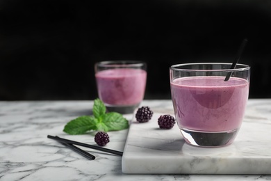 Photo of Glass with tasty blackberry yogurt smoothie on table