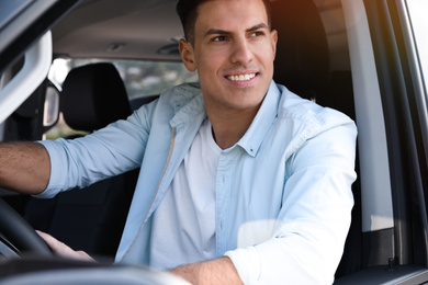 Photo of Handsome man driving his modern car, closeup