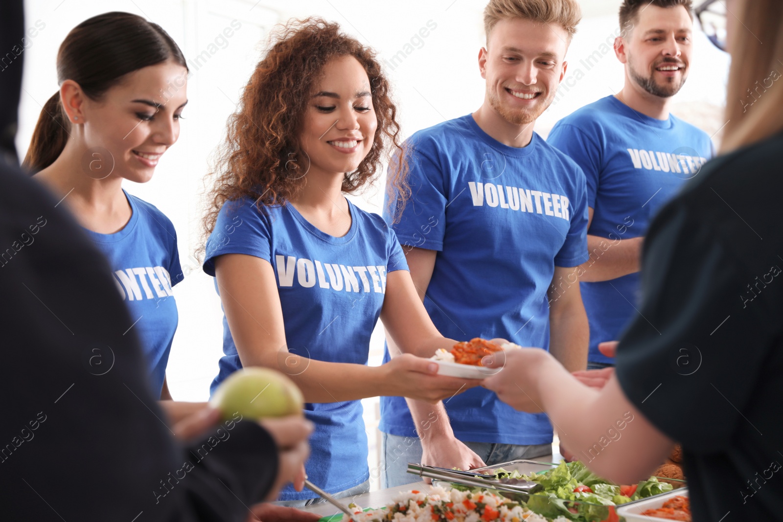 Photo of Volunteers serving food to poor people indoors