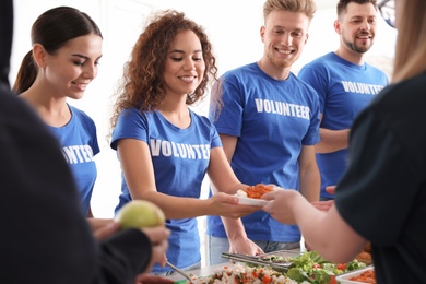 Volunteers serving food to poor people indoors