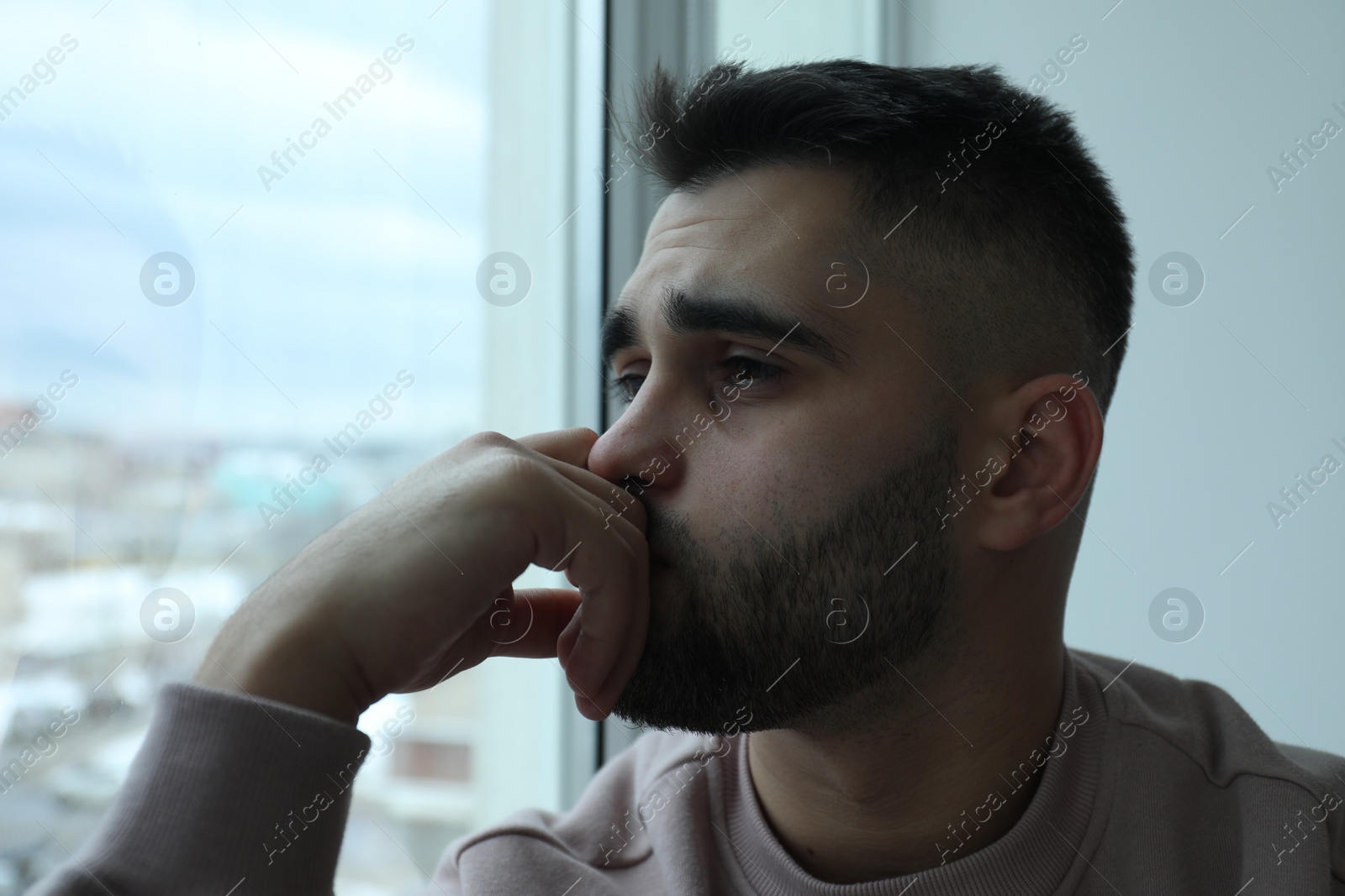 Photo of Portrait of sad man near window at home