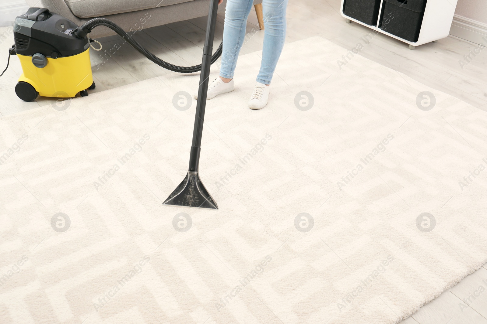 Photo of Woman removing dirt from carpet with vacuum cleaner indoors, closeup. Space for text