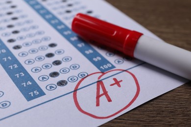 School grade. Answer sheet with red letter A, plus symbol and marker on wooden table, closeup