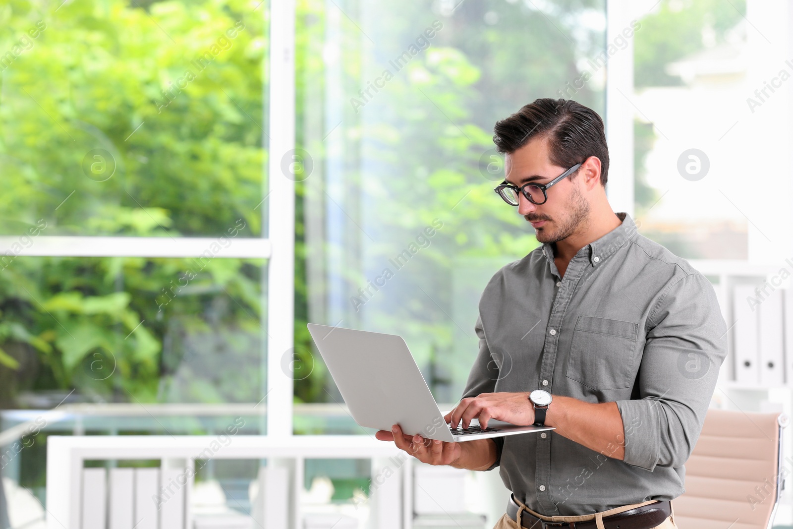 Photo of Handsome young man working with laptop indoors. Space for text