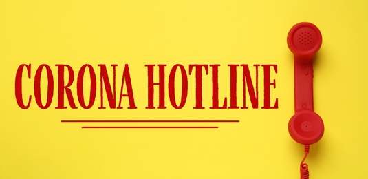 Image of Covid-19 Hotline. Red handset and text on yellow background, top view