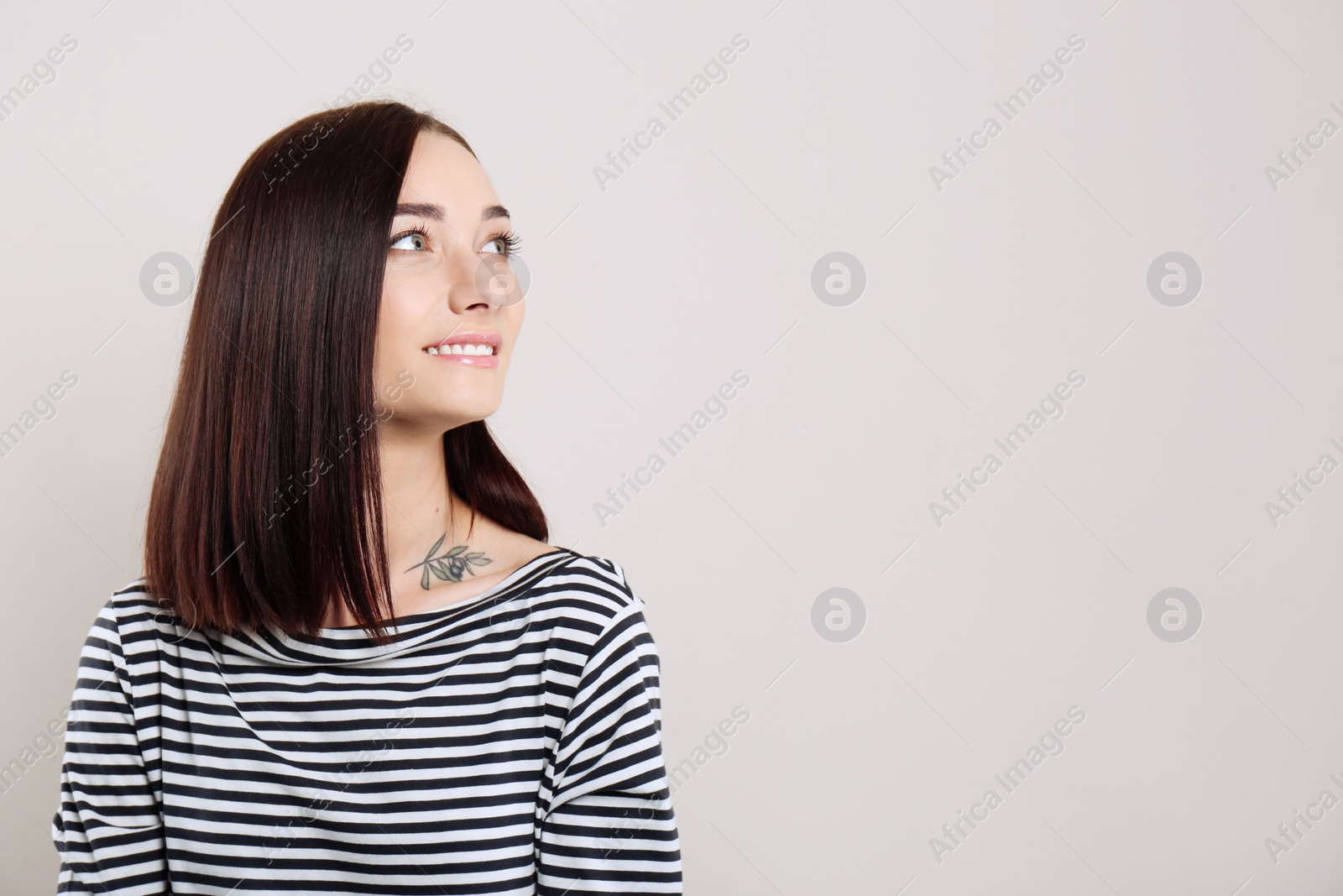 Photo of Portrait of pretty young woman with gorgeous chestnut hair and charming smile on light background, space for text