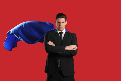 Man wearing superhero cape on red background