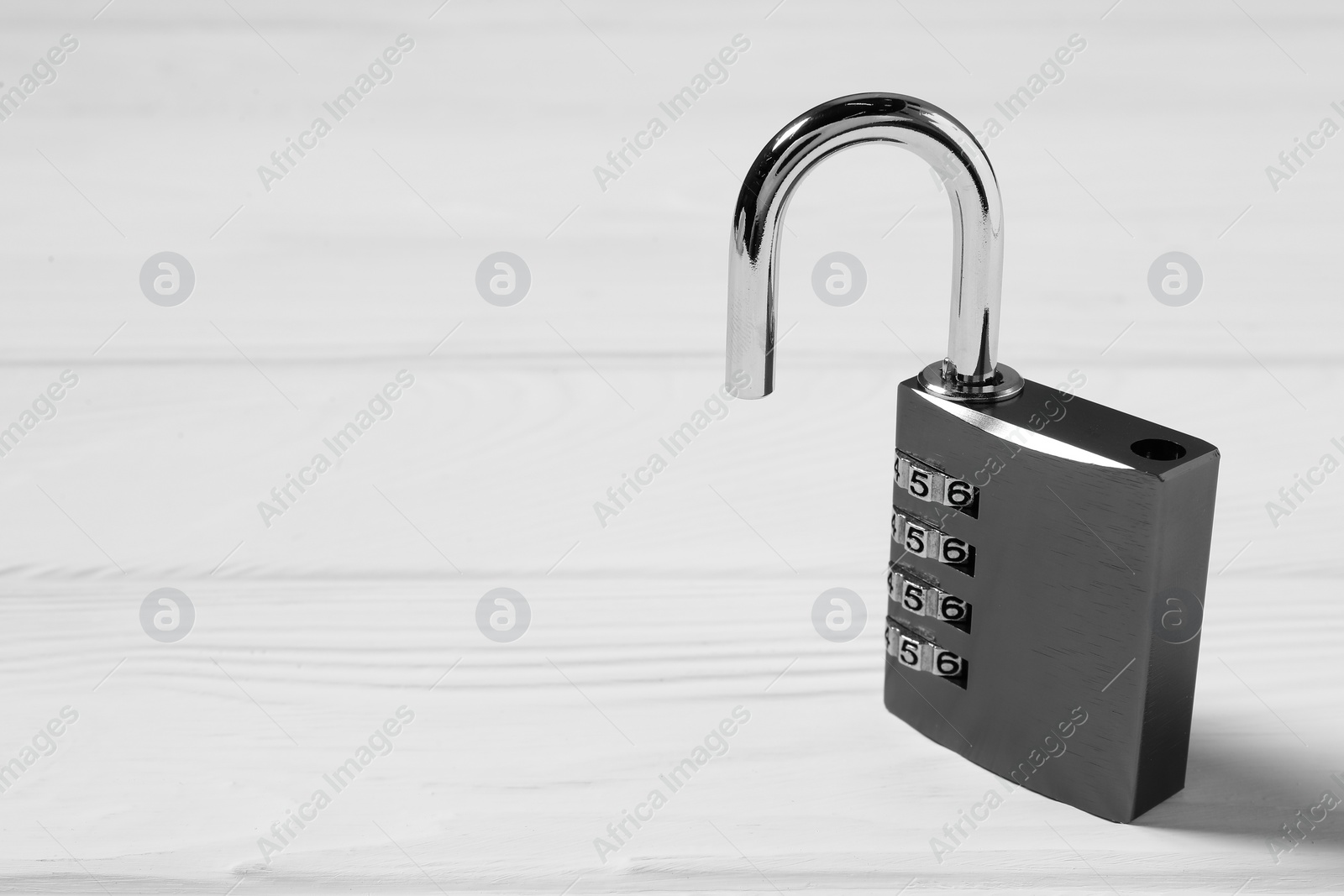 Photo of One steel combination padlock on white wooden table, closeup. Space for text