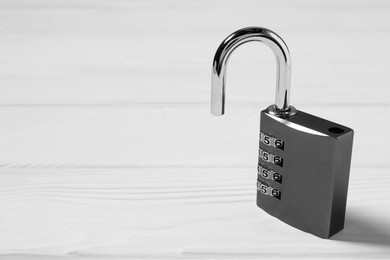 One steel combination padlock on white wooden table, closeup. Space for text