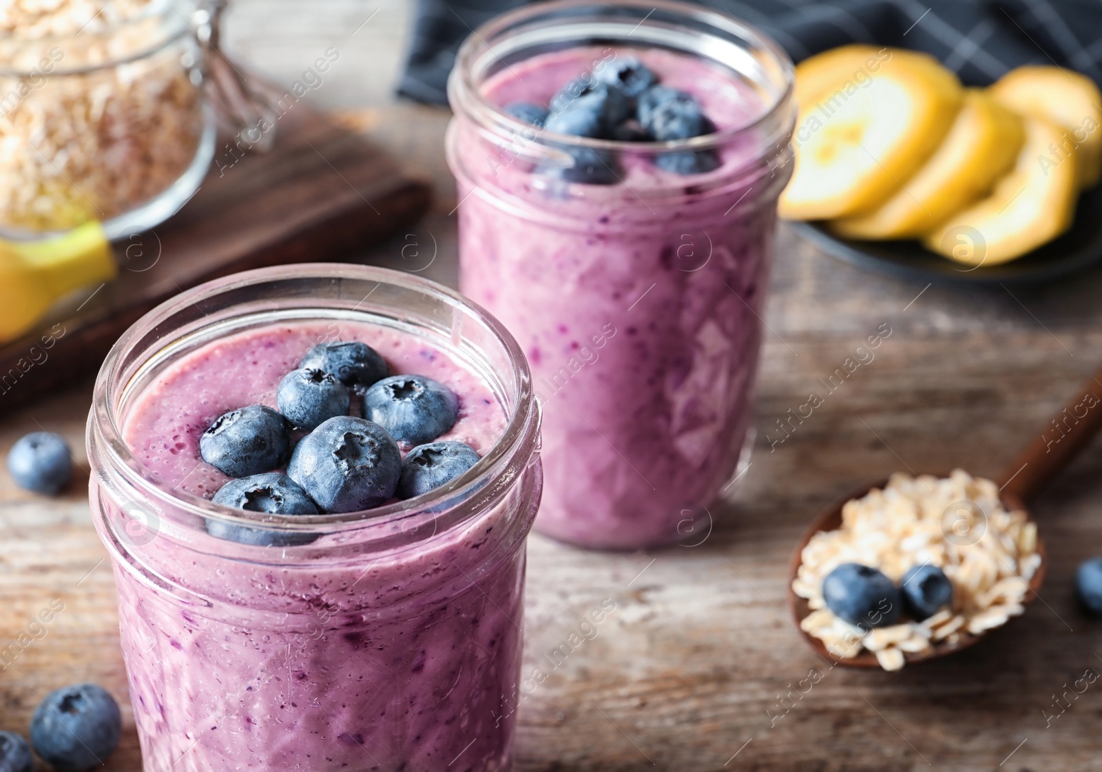 Photo of Jars with blueberry smoothies on table, closeup