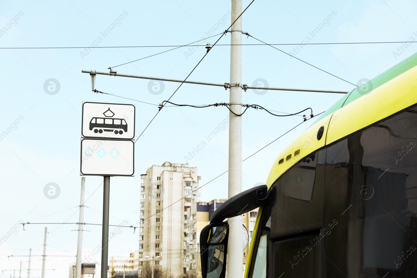 Photo of Modern streetcar near tram stop sign outdoors