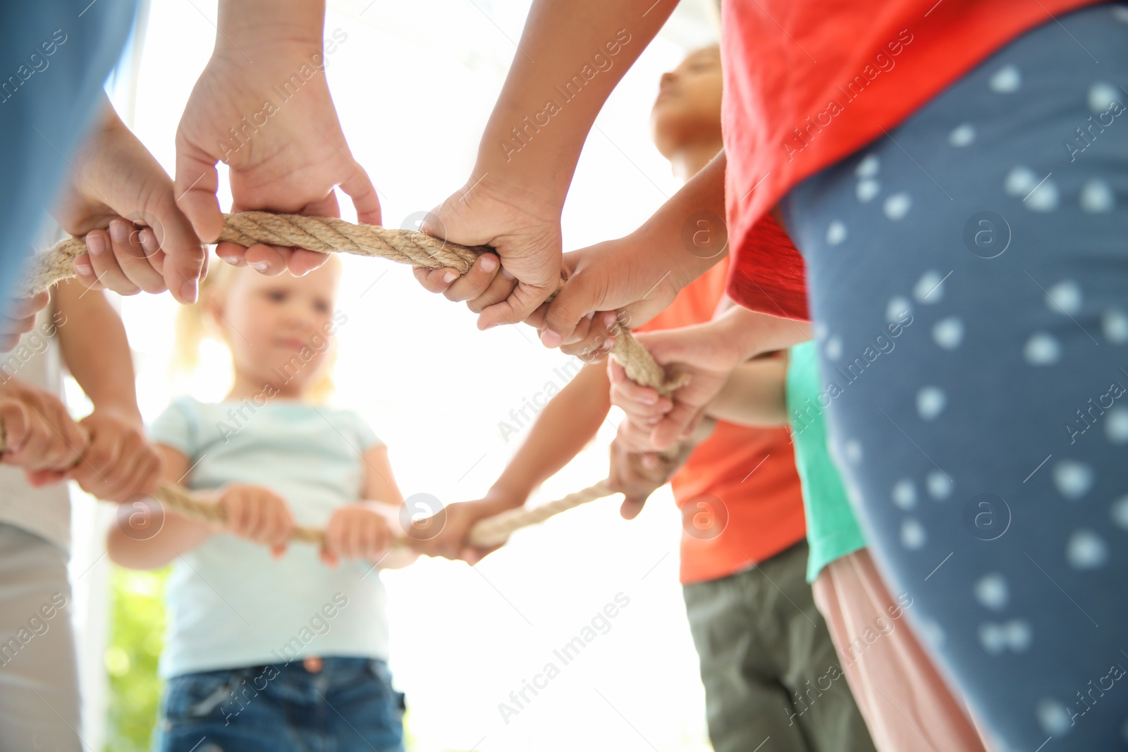 Photo of Little children holding rope on light background, focus on hands. Unity concept