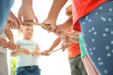 Little children holding rope on light background, focus on hands. Unity concept