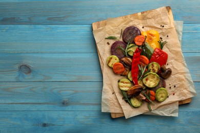 Photo of Delicious grilled vegetables on light blue wooden table, top view. Space for text