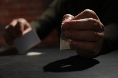 Photo of Addicted man with hard drug and blank card preparing for consumption at grey table, selective focus