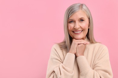 Portrait of beautiful middle aged woman on pink background, space for text