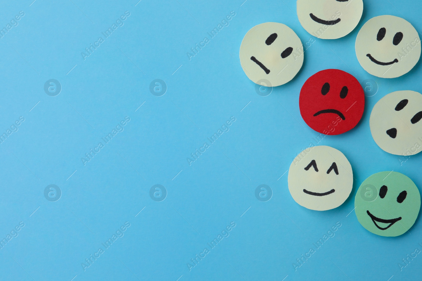 Photo of Many faces with different emotions on light blue background, flat lay. Space for text