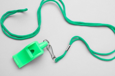 Photo of One green whistle with cord on light grey background, top view