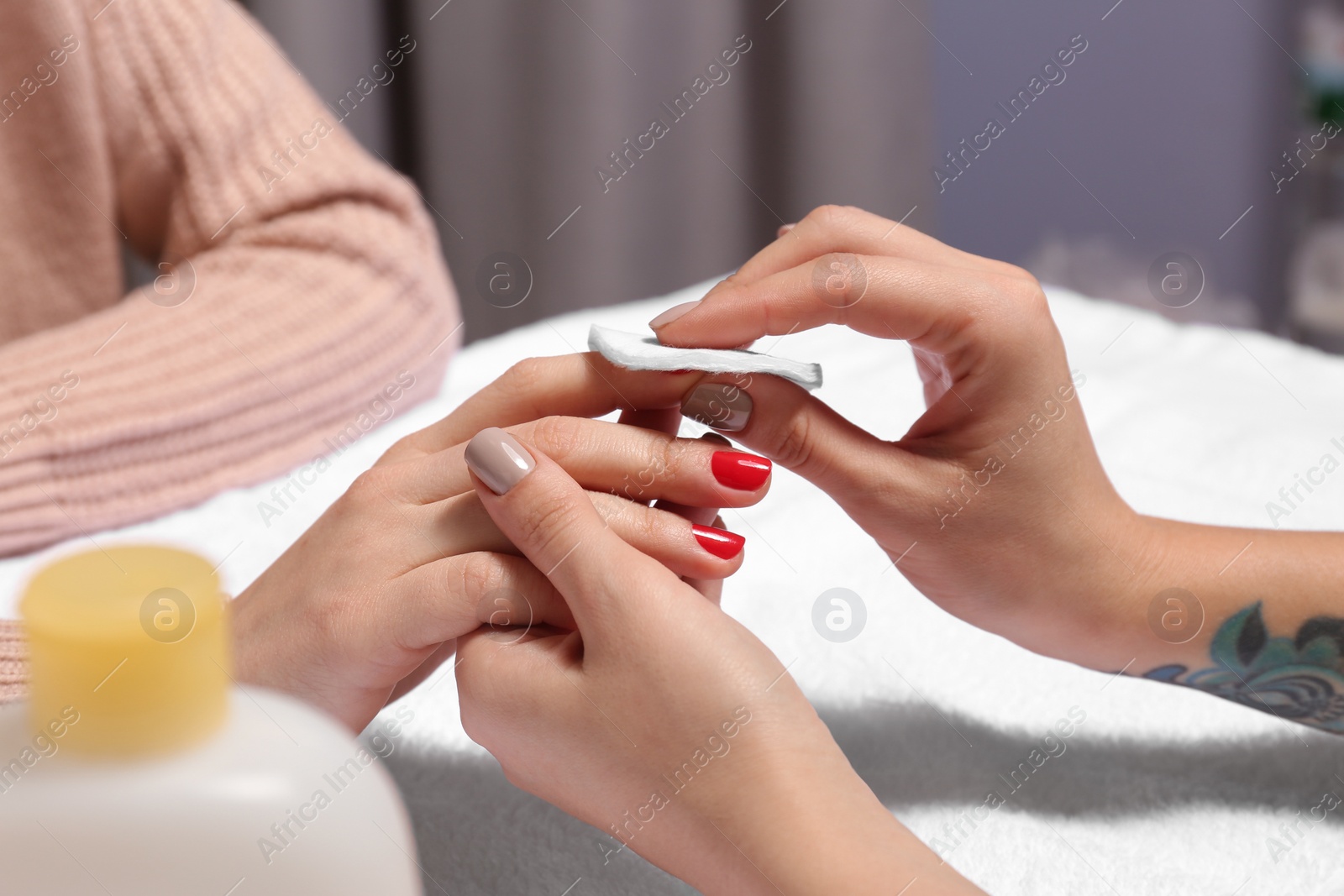 Photo of Manicurist removing polish from client's nails in salon, closeup