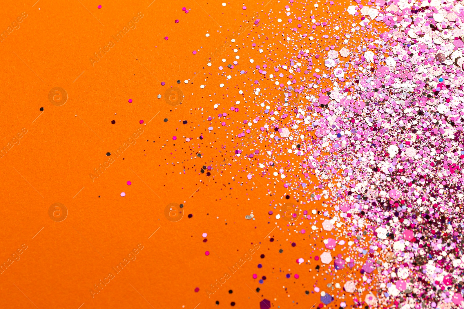 Photo of Shiny bright pink glitter on orange background, flat lay. Space for text
