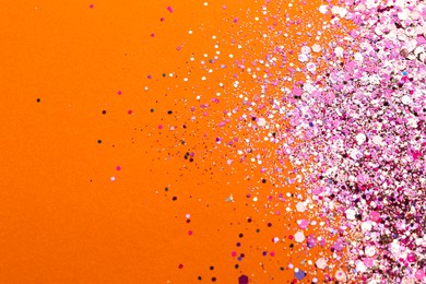 Photo of Shiny bright pink glitter on orange background, flat lay. Space for text