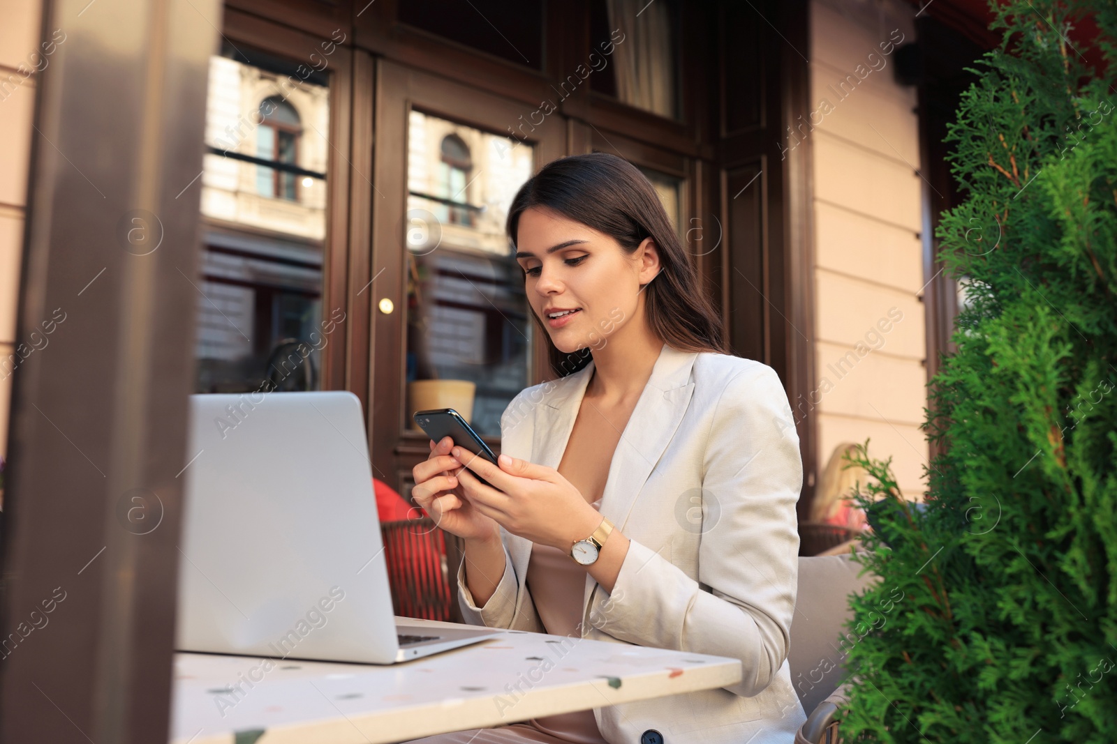 Photo of Beautiful young woman using smartphone in outdoor cafe