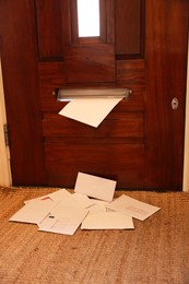 Photo of Wooden door with mail slot and many envelopes indoors