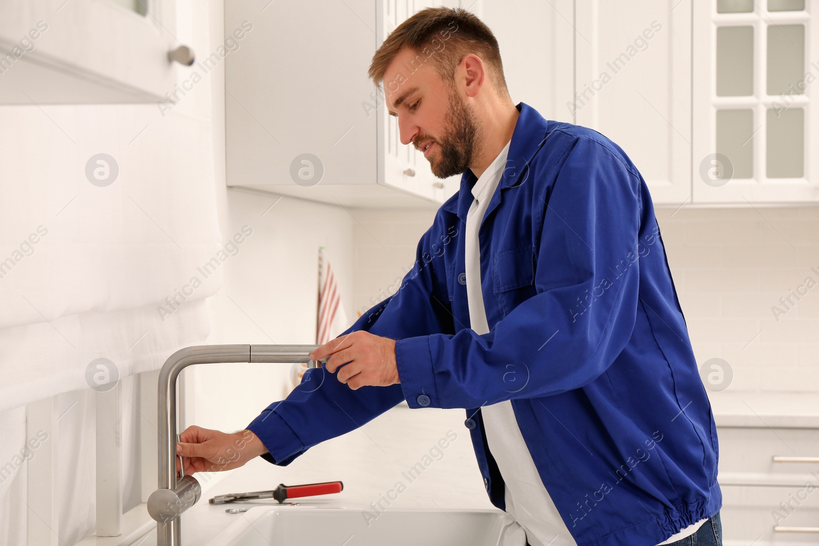 Photo of Plumber checking water tap after installation in kitchen