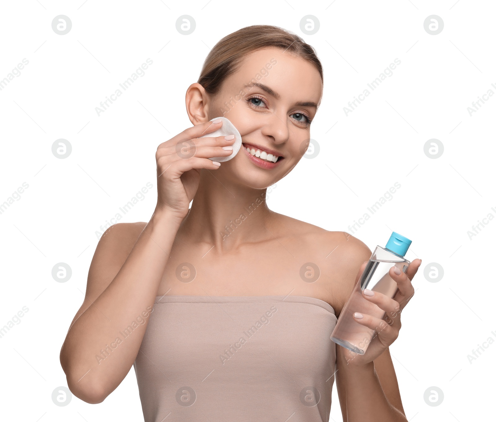 Photo of Smiling woman removing makeup with cotton pad and holding bottle on white background