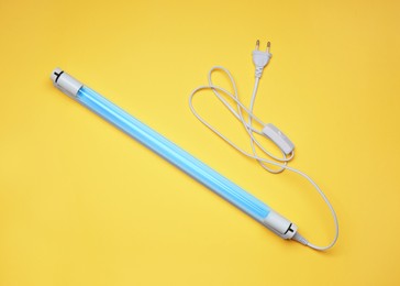 Ultraviolet lamp on yellow background, top view