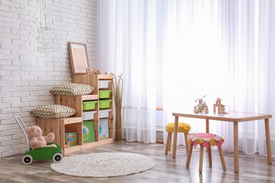 Photo of Modern eco style interior of child room with wooden crates near brick wall