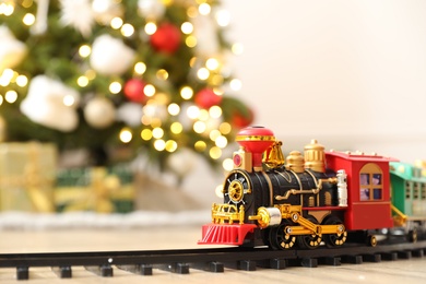 Photo of Toy train and railway on floor against Christmas lights