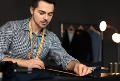 Photo of Young tailor working with sewing pattern in atelier