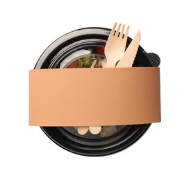 Photo of Tasty food in container with wooden fork and knife isolated on white, top view