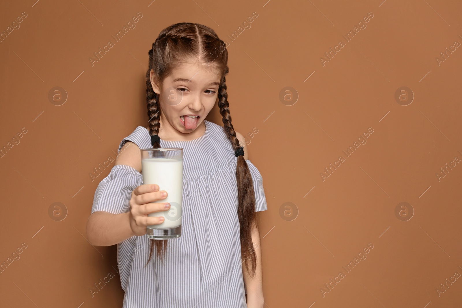 Photo of Little girl with dairy allergy holding glass of milk on color background