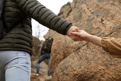 Photo of Group of hikers climbing up mountain, closeup of hands